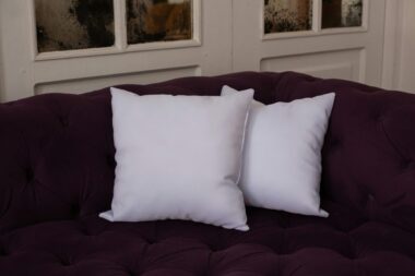 Cozy white pillows on a luxurious purple sofa create a comfortable living space.